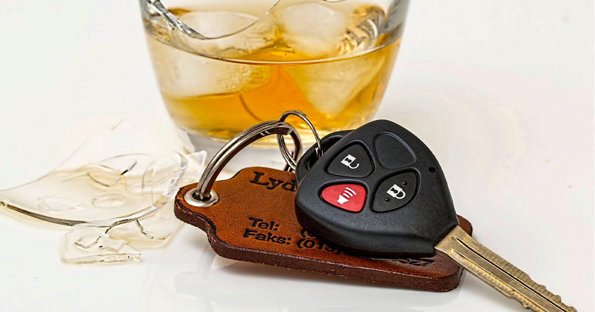 Na fotografiji so avtomobilski ključi in kozarec alkoholne pijače. 